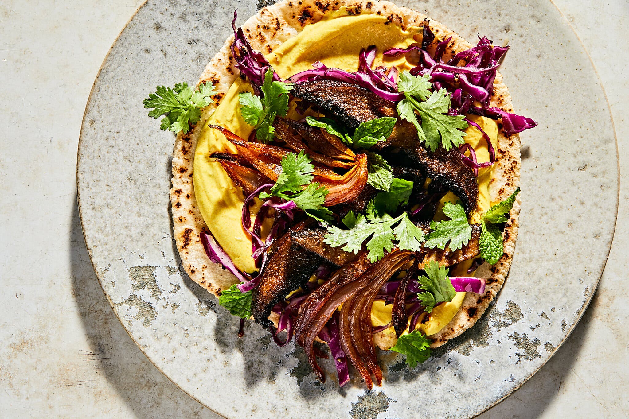 An overhead image of mushrooms and roasted onions on pita.