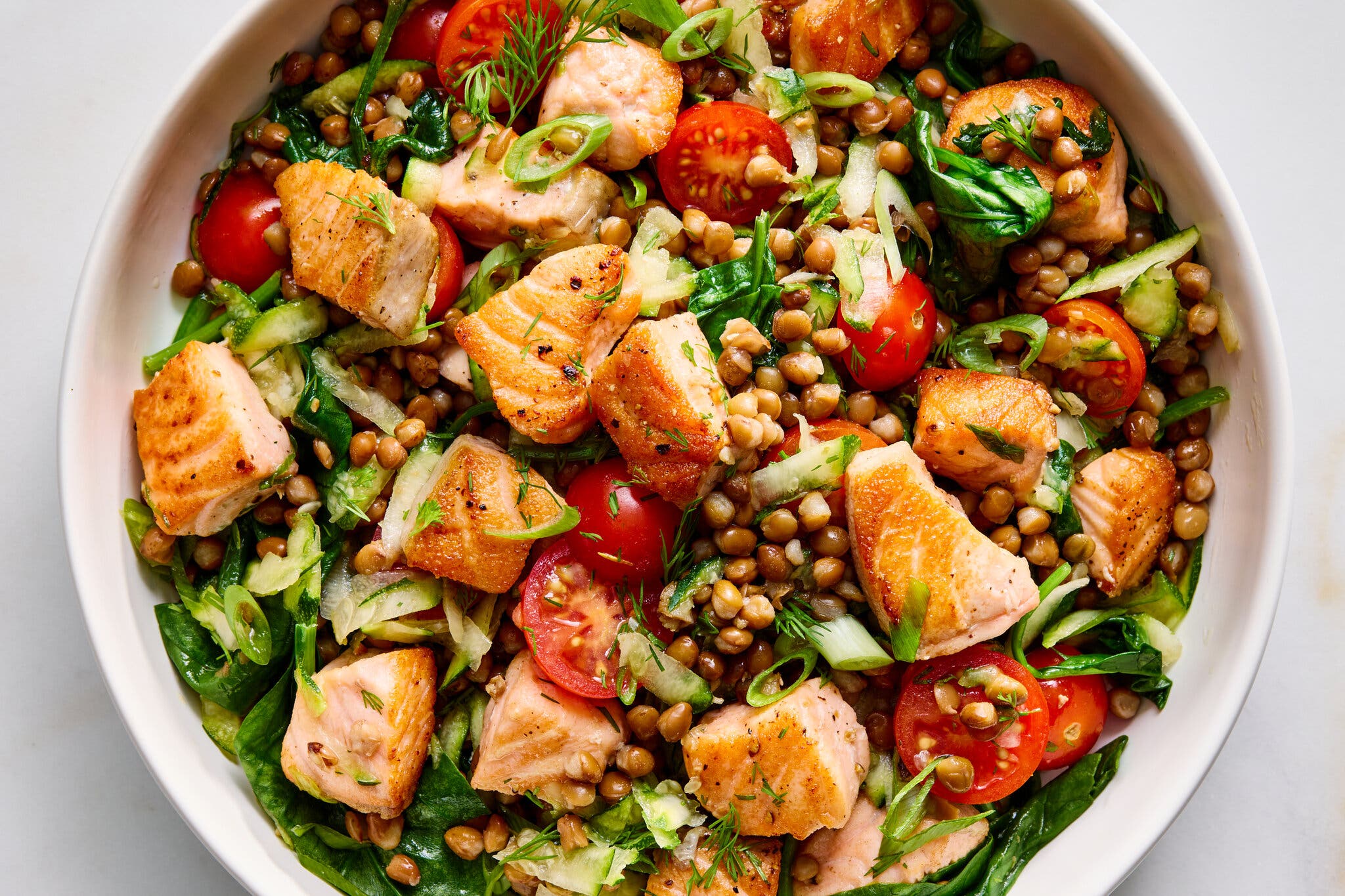 Seared salmon bites tossed in a vibrant salad with brown lentils, cherry tomatoes, spinach and scallions.