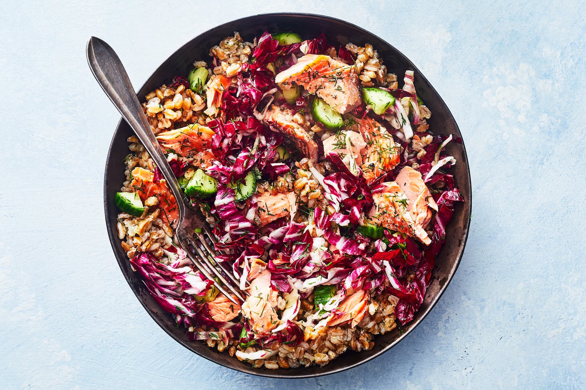 Flaked salmon mixed into a grain salad with farro, bright purple radicchio and chopped cucumbers.