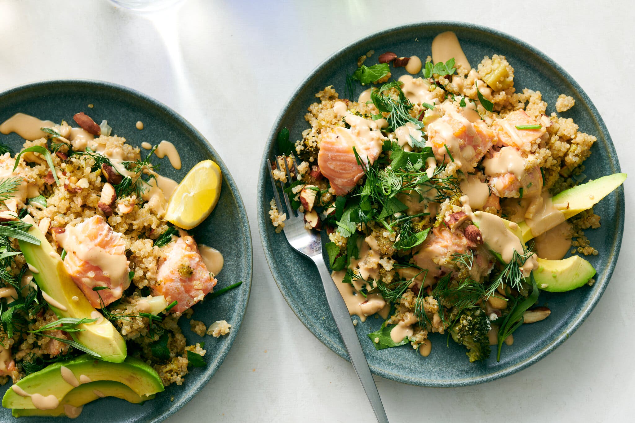 Cubed salmon served over quinoa with avocado slices, almonds and a creamy tahini-style dressing.