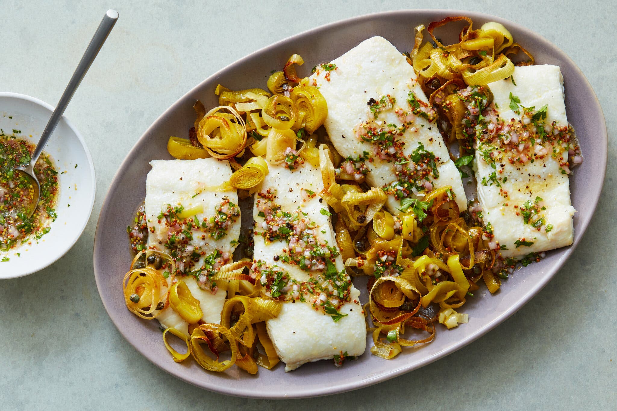 Four white fish fillets topped with a herb and grain mustard relish, served over a bed of melted leeks.