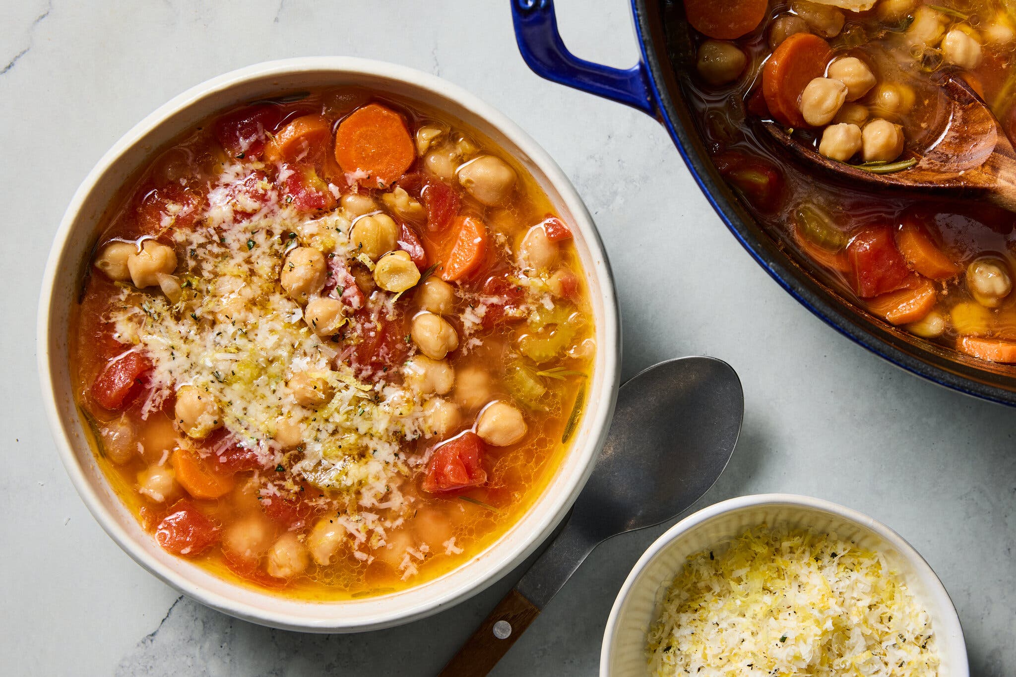 A bowl of chickpea and carrot soup topped with a bright yellow lemon and herb gremolata.