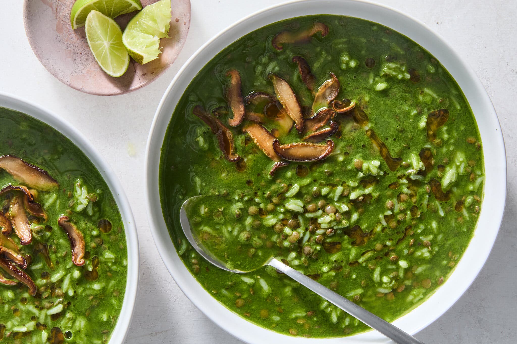 A vibrant green puréed soup with whole lentils and rice, topped with sautéed shiitake mushrooms.