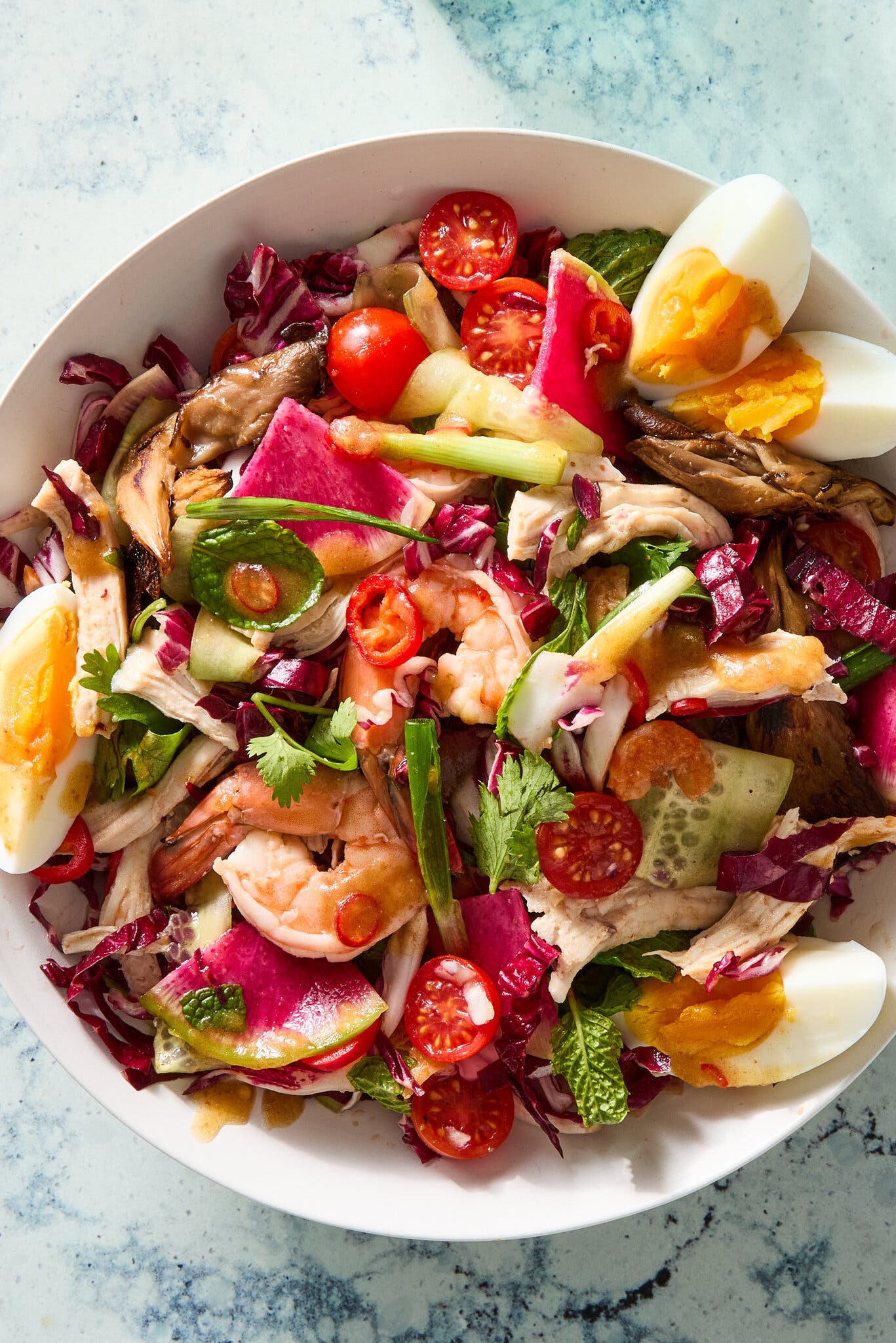 A bowl of salad that includes shrimp and hard-cooked eggs.
