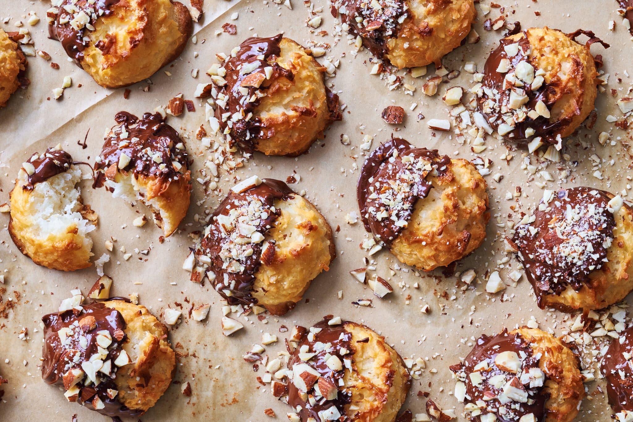 Rows of macaroons, dipped in chocolate and coated with almonds, sit on parchment paper