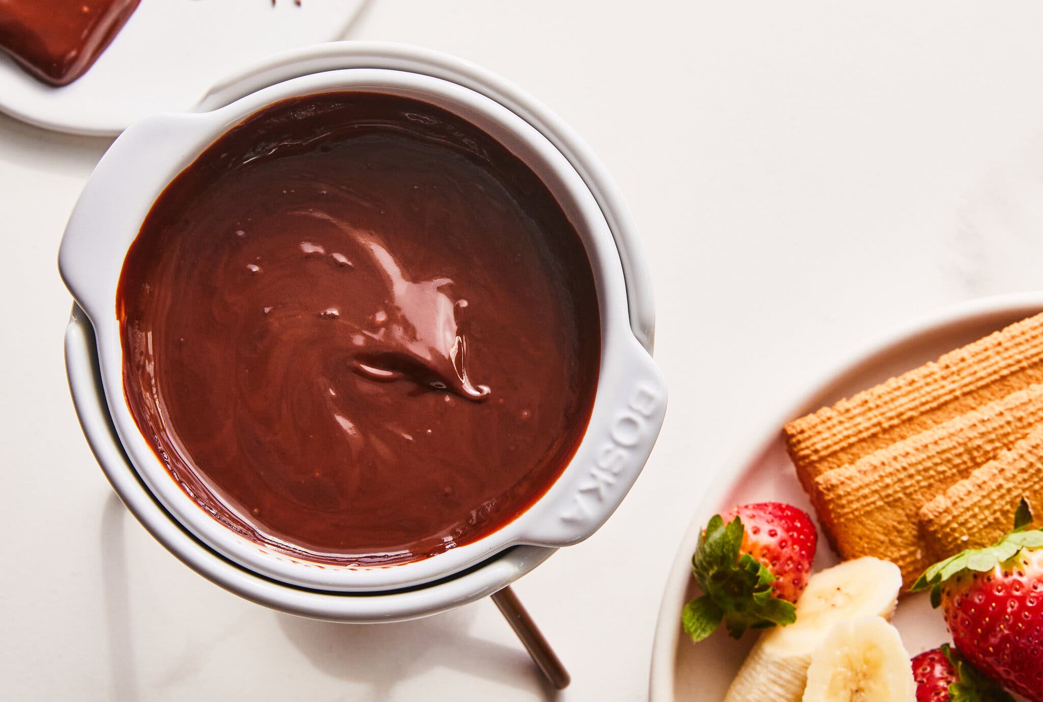 A side image of a slice of chocolate cake with chocolate buttercream on a plate. There is a spoonful of cake on the plate.