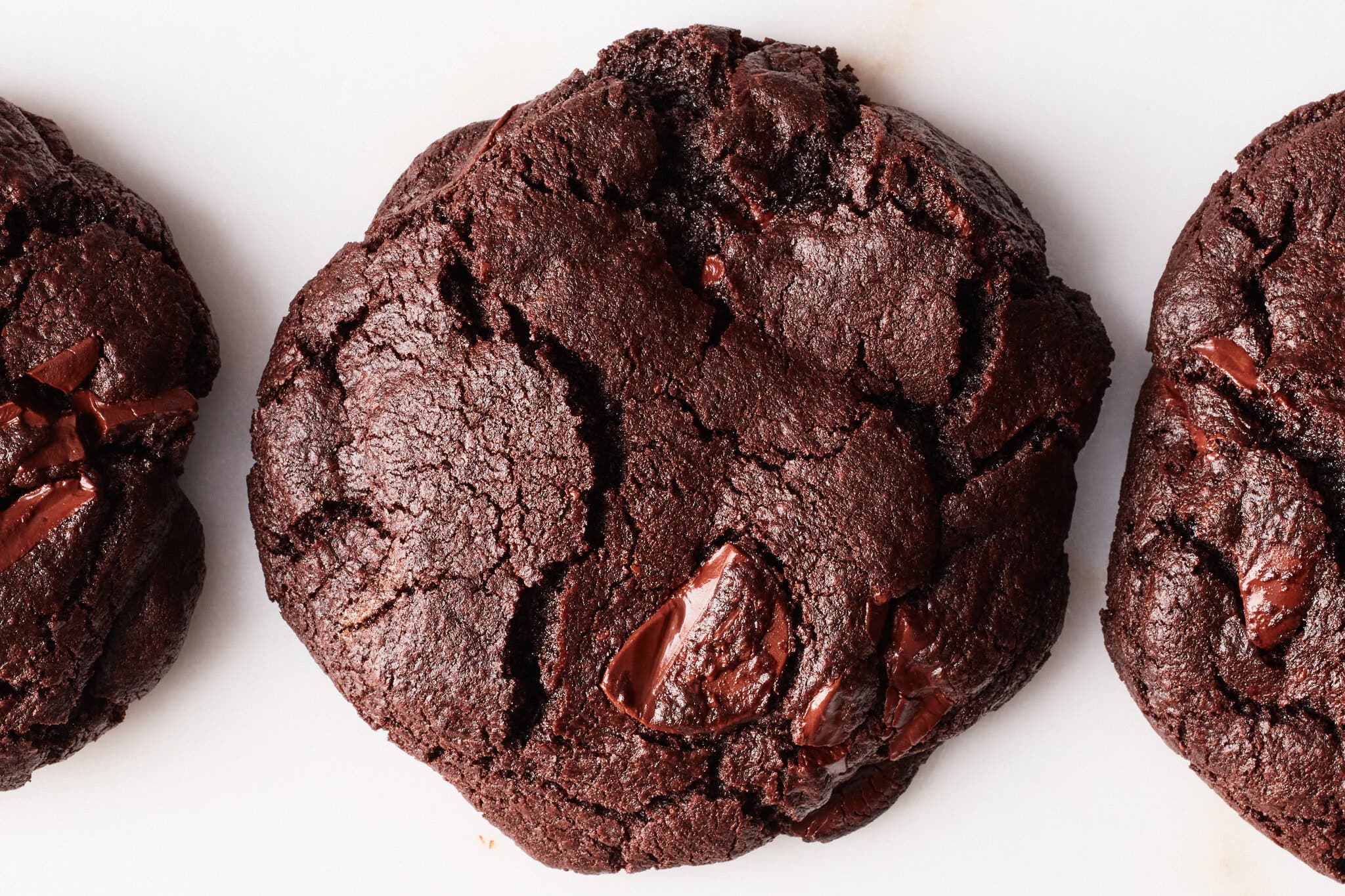 A close-up image of a double chocolate chip cookie, studded with melty chocolate discs.